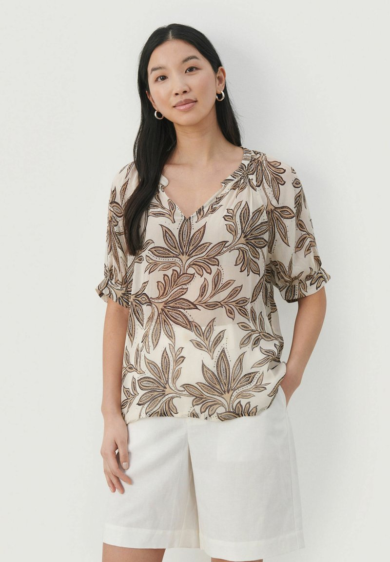 Bluse med blomsterprint i creme- og brunnuancer, der har en V-udskæring og korte, rullede ærmer. Blødt, let materiale.