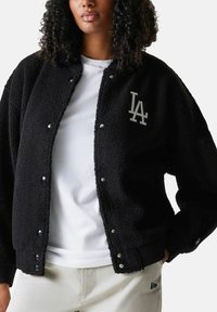 Schwarze Fleecejacke mit Druckknöpfen, ausgestattet mit einem grauen "LA"-Logo. Entworfen mit einer lockeren Passform und gerippten Bündchen, die Textur und Wärme bieten.