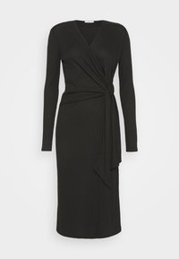 Robe midi noire à manches longues avec encolure en V et détail de nœud sur le côté créant un effet taille froncée sur fond uni.