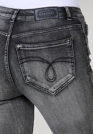 Čierne denimmové nohavice s veľkou zadnou vreckom s charakteristickým zakriveným švom a značkovou etiketou na páse.