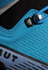 La section des chaussures bleu et noir présente une surface texturée, des accents réfléchissants et un mécanisme de verrouillage des lacets pour un ajustement sécurisé.
