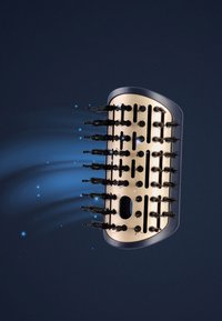 Hårborste med en guldbas och svarta borst, med en böjd design, ventilationshål och ett smidigt svart handtag. Accenter framhävda med ljus.