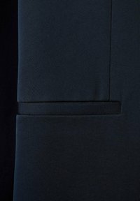 Tumma laivansiniset kangas, jossa on hienovarainen pinta. Oma puhdas sauma ja vaakasuora taskun aukko ilman näkyvää varustusta tai ompelu деталей.