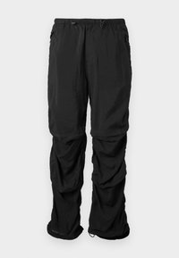 Pantalons utilitaires noirs en tissu léger dotés d'une ceinture élastique, de cordons de serrage ajustables et de poches latérales, offrant une coupe décontractée.
