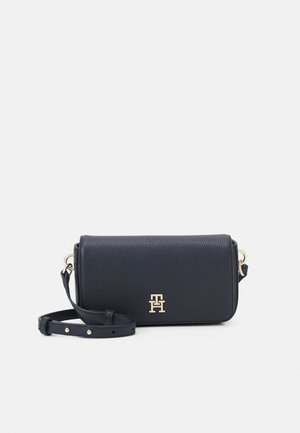 Petit sac bandoulière rectangulaire en cuir noir avec sangle réglable et logo ainsi que ferrures dorées sur fond blanc.
