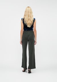 Svart og hvit mønstrete vide bukser med høy midje, kombinert med en blå fløyelsgenser, og brukt med svarte høyhælede sko.