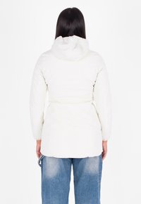 Witte donsjack met capuchon, cinched taille en elastische manchetten. Glad textuur en minimalistisch ontwerp, gecombineerd met blauwe denim jeans.