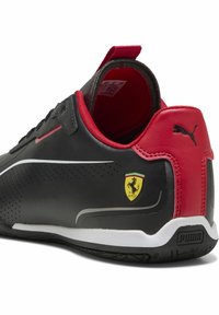 Sort lædersko med røde accenter, perforerede detaljer og en hvid stribe. Har Ferrari-logoet og Puma-branding på hælen.