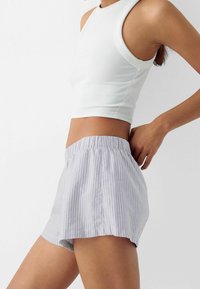 Ljusblå och vita randiga shorts i bomull med elastisk midja, med en avslappnad passform och sidodelade fållar för rörelsefrihet.