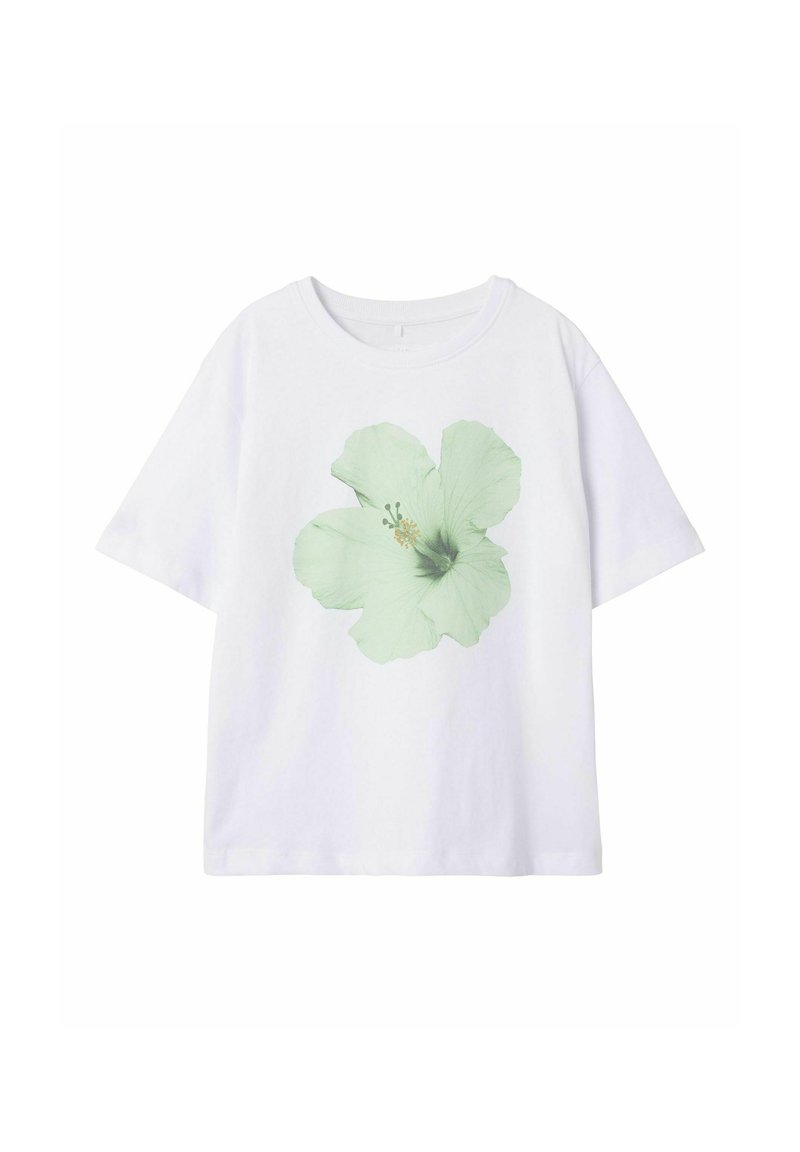 Balta kokvilnas T-kreklā ar gaiši zaļas hibiska zieda grafiku priekšpusē. Ievērojama klasiskā apaļā kakla izgriezuma un īsām piedurknēm.