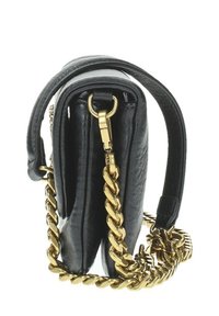 Borsa a mano nera in pelle con una forma strutturata, tracolla in catena dorata e un evidenziato dettaglio di chiusura con zip. La superficie testurizzata aggiunge interesse visivo.