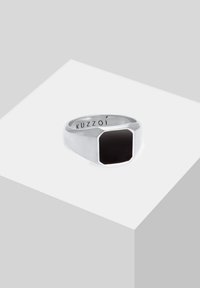 Hõberõngas kaheksanurga kujulise musta kivikesega keskosas. Sile viimistlus ja sees on graveeritud brändinimi. Geomeetrilise kujundusega.