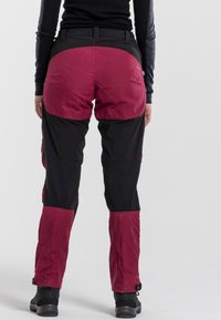 Black and maroon outdoor pants with a textured finish. Features reinforced knees and a cinched ankle with adjustable hardware.