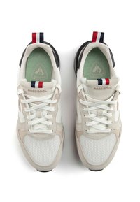 Vita och beige sneakers med mesh- och mockamaterial, med svarta sulor och en trikolor hälla. Snören och präglad logo på sidan.