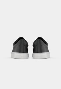 Black leather sneakers with a smooth finish, low-top design, and white rubber sole. Features minimal branding at the heel.