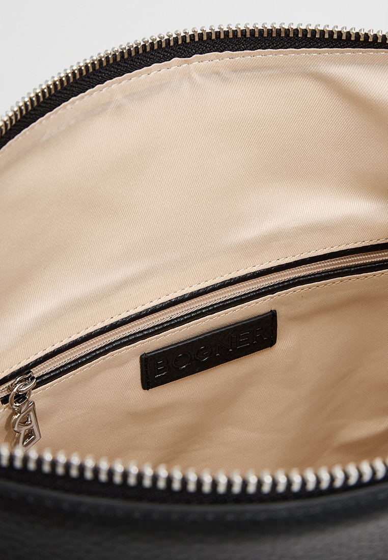 Schwarze Stofftasche mit einem cremefarbenen Innenfutter, ausgestattet mit einem silbernen Reißverschluss und einem schwarzen Lederetikett, das mit "BOGNER" geprägt ist.