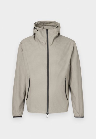 Kerge, beež vihmajope tekstuurse viimistlusega, reguleeritava kapuutsi, ees tõmblukuga ja kahe küljetaskuga, millel on mustad aktsendid.