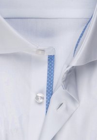 Weißes Hemd mit einem hellblau gemusterten Akzent im inneren Kragen, mit einem einzigen Knopf und einer glatten, gewebten Textur.