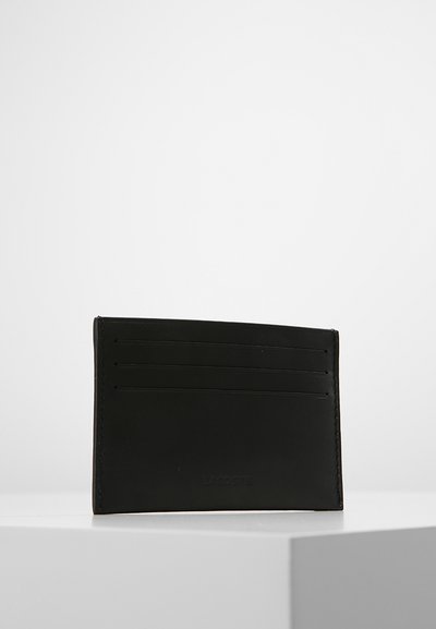 Portefeuille en cuir noir avec six emplacements pour cartes et une texture. Présente un design minimaliste et un logo de marque embossé.