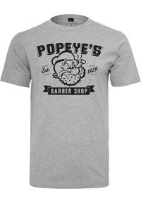 Grijze katoenen t-shirt met een grafisch ontwerp van een cartoonfiguur met een pijp en tekst die luidt "POPEYE'S BARBER SHOP", opgericht in 1929.