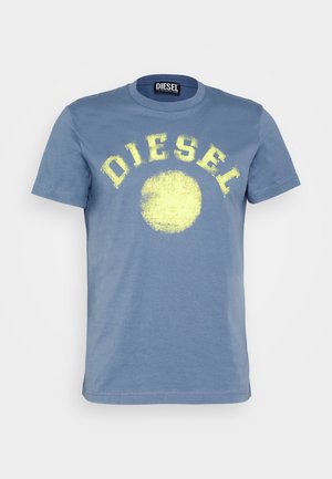 T-shirt bleu à manches courtes avec un texte jaune usé "DIESEL" en arc au-dessus d'un cercle jaune délavé à l'avant.