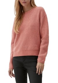 Texturerad, mjuk stickad tröja i ljusrosa med rund halsringning och långa ärmar, ihop med svarta åtsittande byxor.