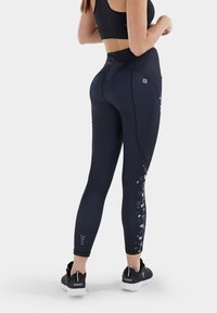 Leggings neri con una vita alta, caratterizzati da un design testurizzato sul lato, cuciture a contrasto e una silhouette aderente.