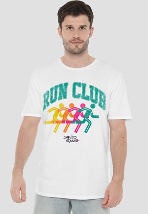 Weißes Baumwoll-T-Shirt mit dem Schriftzug "RUN CLUB" in Türkis und bunten Lauffiguren in Gelb, Orange, Pink und Grün. Darunter das Logo von "Squid Game".