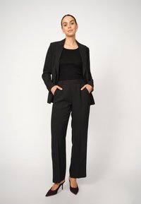 Mustaline must ülikond pikade varrukatega, laiad püksid ja kehaümber olev must tee. Omab taskuid ja sobib maroonide kõrgete kontsadega kingadega.