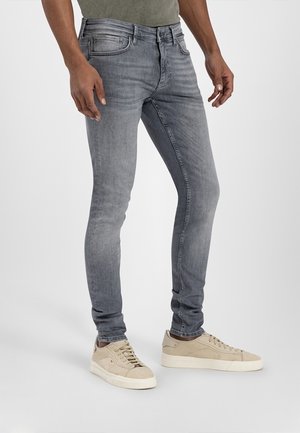 Jeans in denim grigio slim-fit con una finitura sbiadita, design a cinque tasche e dettagli cuciti, abbinati a sneakers di colore chiaro.