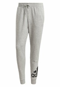 Lysgrå Adidas joggingbukser med elastisk talje, snor, tætsiddende ben, manchetter ved anklerne og sort logo på venstre ben.