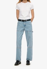 Jeans de mezclilla azul claro con diseño de pierna recta, presentan costuras cosidas y una cinturilla de altura media. Combinados con un cinturón negro.