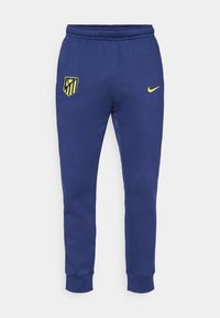 Mørkeblå joggebukser med elastisk liv, smal passform, med en gul Nike-logo og et Atlético Madrid-skjold på venstre lår.