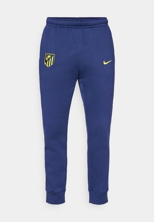 Marineblaue Sweatpants mit elastischem Bund, schmal zulaufender Passform, mit einem gelben Nike-Logo und einem Atlético Madrid-Wappen auf dem linken Oberschenkel.
