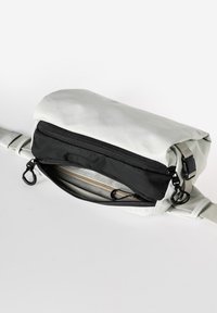 Borsa a tracolla bianca e nera con finitura testurizzata. Caratterizzata da un compartimento principale con zip, tracolla regolabile e colori bicolore.