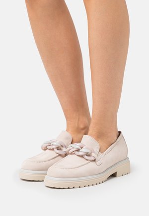 Mocassins en daim rose clair avec une semelle blanche épaisse et un accent de chaîne décorative à l'avant. Design simple avec une texture lisse.