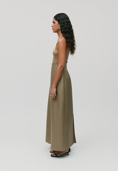 Abito maxi in un colore oliva solido, con spalline regolabili, un corpetto aderente e una spaccatura laterale. Abbinato a sandali con tacco neri.