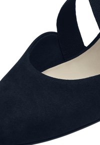 Černá semišová bota s špičatou špičkou, elastickým páskem a hladkou béžovou stélkou. Má nízký podpatek a jemnou strukturu.