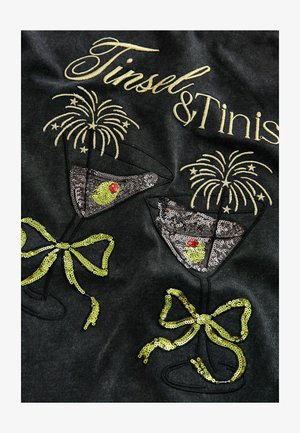Zwarte stof met geborduurde tekst "Tinsel & Tinis", met pailletten martini-glazen, gele accenten en sterretjesontwerpen.