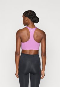 Μωβ αθλητικό σουτιέν με σχέδιο racerback και εφαρμοστή γραμμή, συνδυασμένο με μαύρο κολάν με ψηλή μέση. Ομαλή υφή, ελάχιστη σήμανση.