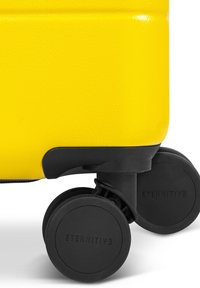 Valise jaune avec une surface texturée, dotée d'une base en plastique noir et de deux roues arrondies estampillées "ETERNITIVE."