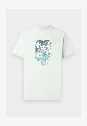Svijetlozelena pamučna majica s grafičkim dizajnom lubanje, kuće i zvijezda. Okrugli izrez, kratki rukavi i opušteni kroj.