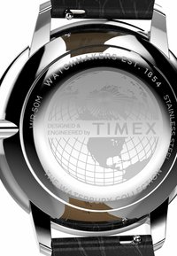 Stainless steel watch back featuring a globe design, engraved text, and a black textured leather strap attached to metallic lugs.
