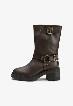 Brown leather ankle boot with a round toe, buckle accents, a thick heel, and a textured sole for traction.