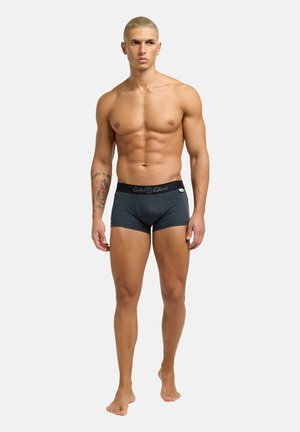 Mørkegrå boxer briefs med en sort elastisk talje, der har brandnavnet. Tekstureret stof, tætsiddende design. Modellen er barefodet.