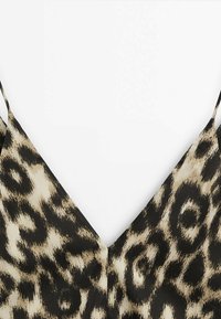 Leopardprint top met een diepe V-halslijn, met een mix van beige en zwarte kleuren, en dunne verstelbare bandjes. Soepele textuur.