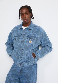 Jeansjacke in Hellblau mit einem tonal gehaltenen Tierdruckmuster, ausgestattet mit einem Kragen, Brusttaschen und einer Knopfleiste.