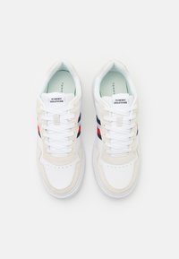 Sneaker bianche con dettagli in suede beige e blu scuro. Presentano strisce rosse e blu, lacci piatti e una soletta imbottita.