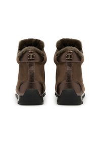 Stivali ankle in pelle marrone con colletto foderato in pelliccia, pannello posteriore testurizzato e suola in gomma nera con grip. Dettaglio del logo dorato sul tacco.