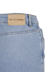 Světle modré džíny z denimu s koženou nášivkou s embosovaným nápisem "2Y STUDIOS", kontrastním šitím a standardním detailem kapes.